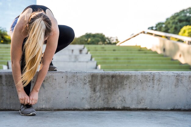 Giovane donna che lega le sue scarpe da ginnastica