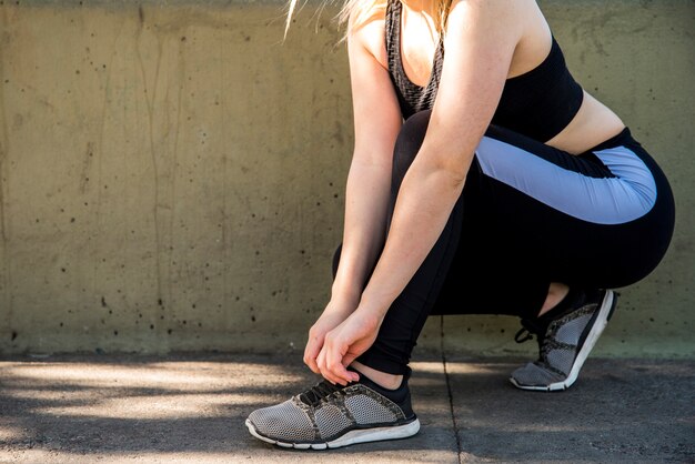 Giovane donna che lega le sue scarpe da ginnastica