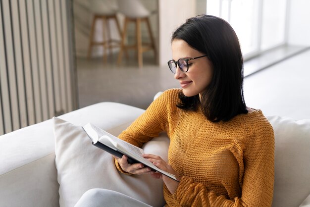 Giovane donna che legge un libro a casa