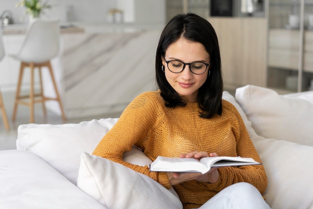 Giovane donna che legge un libro a casa