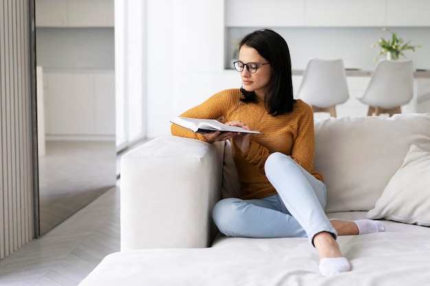 Giovane donna che legge un libro a casa