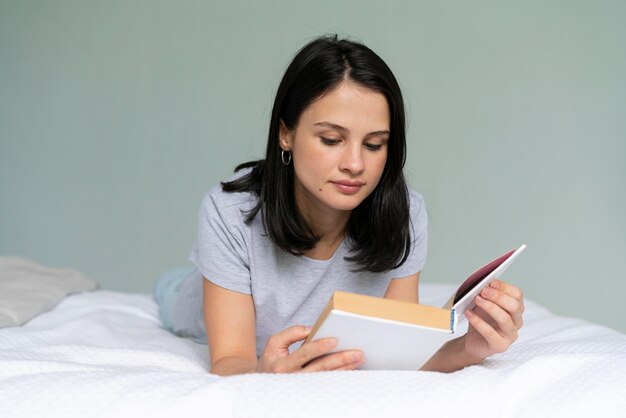 Giovane donna che legge un libro a casa