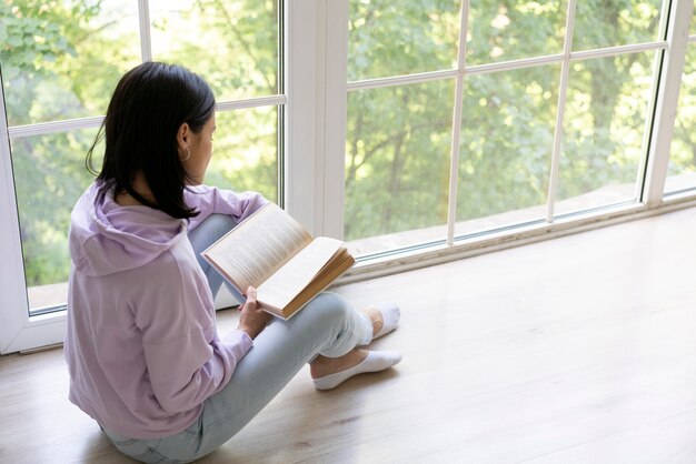 Giovane donna che legge un libro a casa
