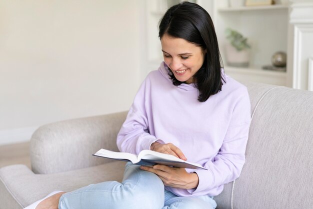 Giovane donna che legge un libro a casa