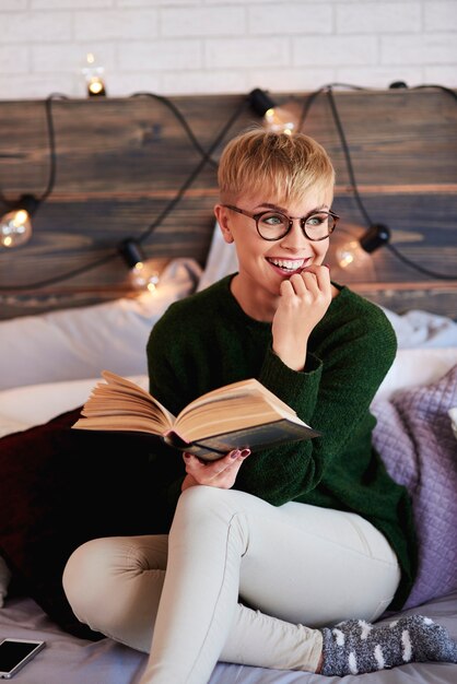 Giovane donna che legge un libro in camera da letto