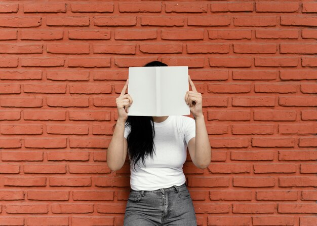 Giovane donna che legge un libro interessante all'aperto