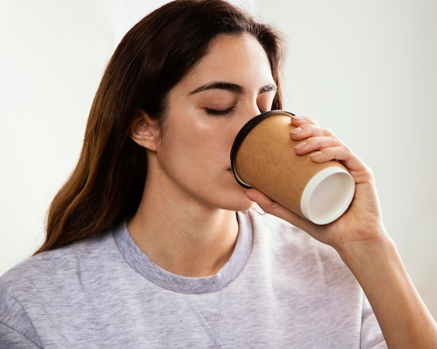 Giovane donna che mangia caffè a casa