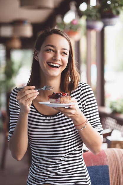 Giovane donna che mangia cheesecake alla fragola