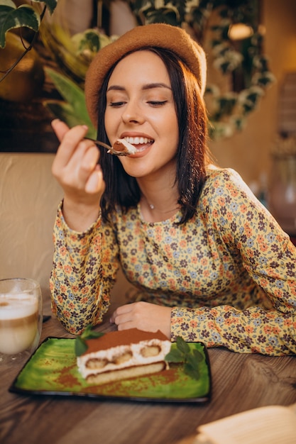 Giovane donna che mangia delizioso tiramisù in un caffè