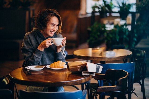 Giovane donna che mangia i croissant ad un caffè