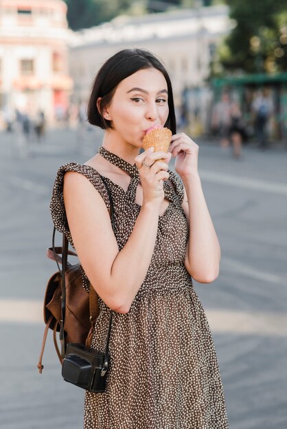 Giovane donna che mangia il gelato sulla strada