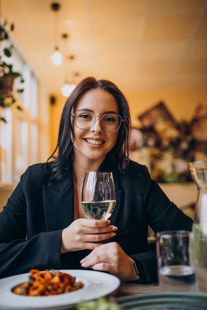 Giovane donna che mangia pasta in un caffè