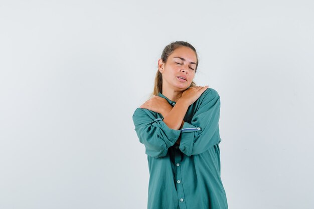 Giovane donna che massaggia le spalle in camicia blu e sembra rilassata