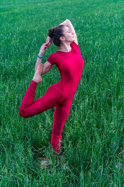 Giovane donna che medita nel campo in erba