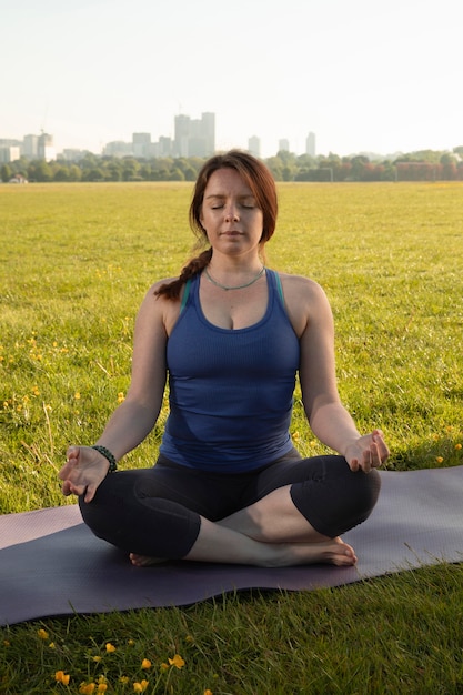 Giovane donna che medita sulla stuoia di yoga all'aperto