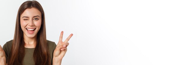 Giovane donna che mostra due dita positivo o gesto di pace su bianco