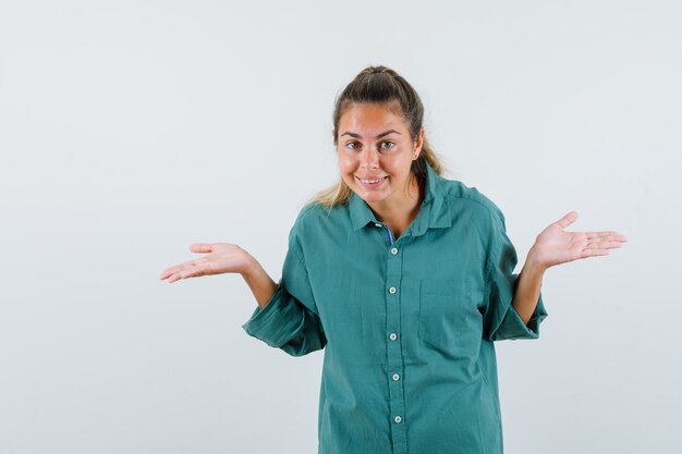 Giovane donna che mostra gesto impotente in vista frontale camicia blu.