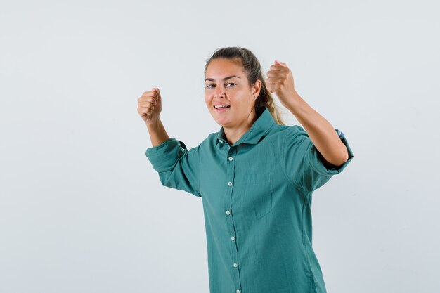 Giovane donna che mostra il gesto del vincitore in camicia blu e che sembra sicura