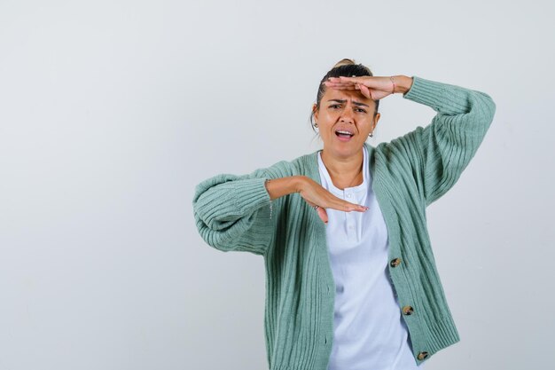 Giovane donna che mostra le mani in camicia bianca e cardigan verde menta e sembra tormentata