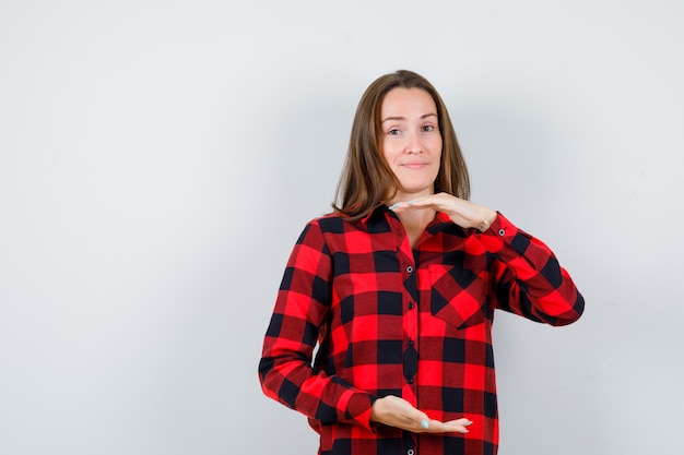 Giovane donna che mostra le scale in camicia a quadri e sembra allegra. vista frontale.