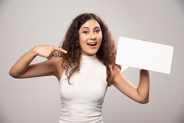 Giovane donna che mostra un manifesto di discorso bianco vuoto vuoto. Foto di alta qualità