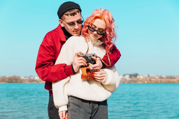 Giovane donna che osserva mentre la macchina fotografica della foto della regolazione dell&#39;uomo