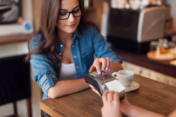 Foto gratuito giovane donna che paga per il caffè con il lettore di carte di credito