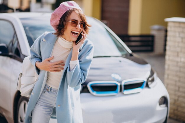 Giovane donna che parla al telefono con la sua auto elettrica