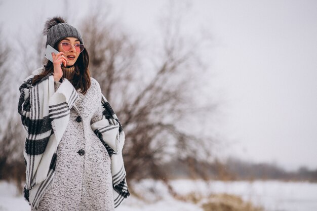 Giovane donna che parla al telefono fuori nel parco di inverno