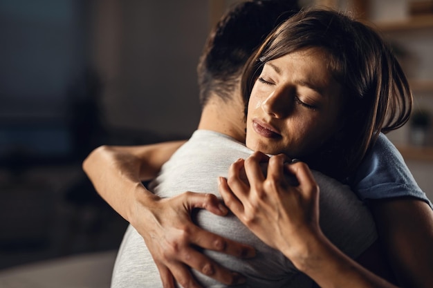 Giovane donna che piange in cerca di conforto e abbraccia il suo ragazzo con gli occhi chiusi