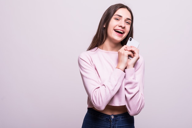 Giovane donna che posa e che sorride sopra il fondo bianco