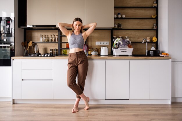 Giovane donna che posa sulla cucina moderna