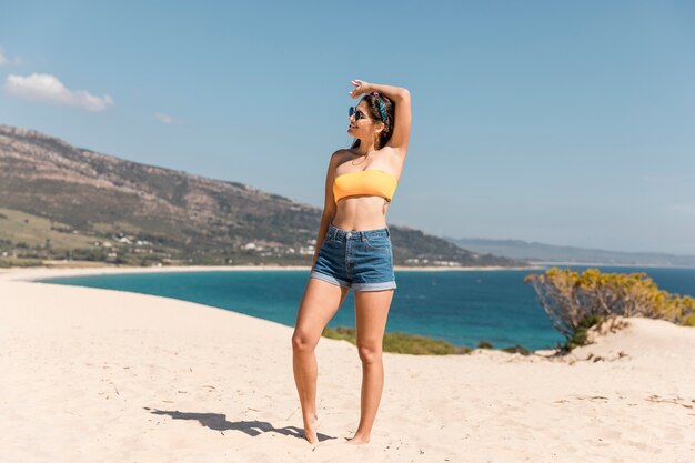 Giovane donna che posa sulla spiaggia sabbiosa