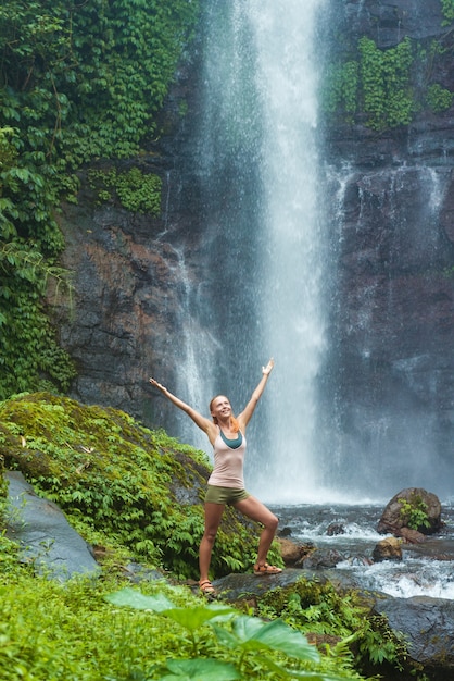 Giovane donna che pratica lo yoga dalla cascata
