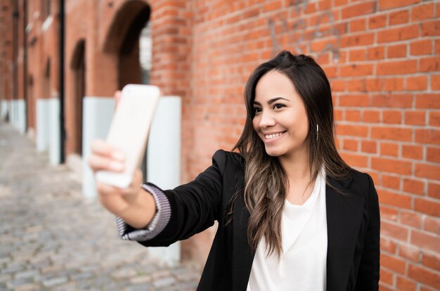 Giovane donna che prende i selfie con il telefono.