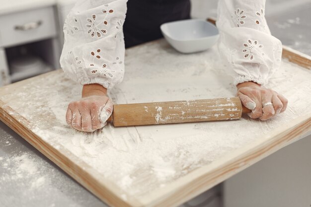 Giovane donna che produce biscotti a forma di per Natale. Soggiorno decorato con decorazioni natalizie sullo sfondo. Donna in grembiule.