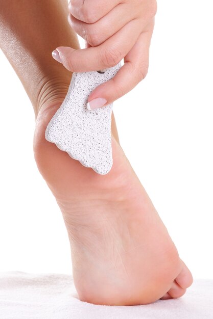 Giovane donna che pulisce i suoi piedi di pomice su un