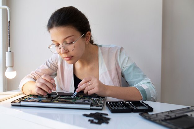 Giovane donna che pulisce la sua tastiera del computer portatile