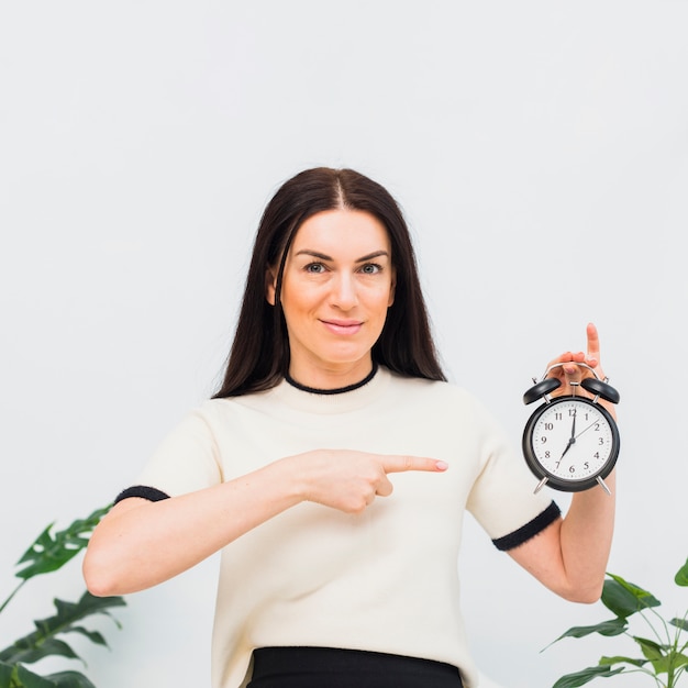 Giovane donna che punta il dito all&#39;orologio