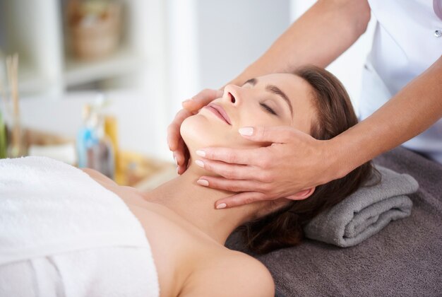 Giovane donna che riceve un massaggio facciale professionale