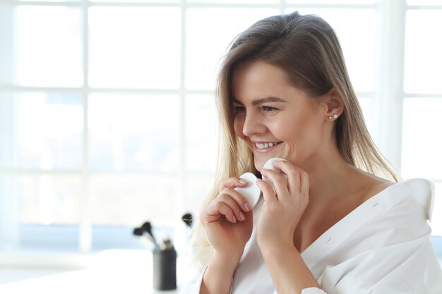 Giovane donna che rimuove il trucco facciale con le salviette struccanti.