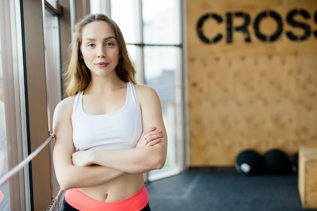 Giovane donna che riposa dopo l'allenamento in palestra. Femmina fitness prendendo una pausa dopo la sessione di allenamento nel centro benessere.