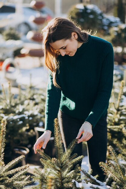 Giovane donna che sceglie un albero di Natale in una serra