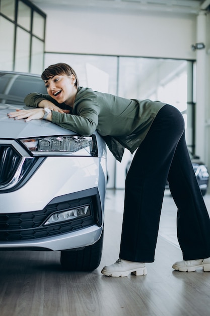 Giovane donna che sceglie un'auto in uno showroom di auto