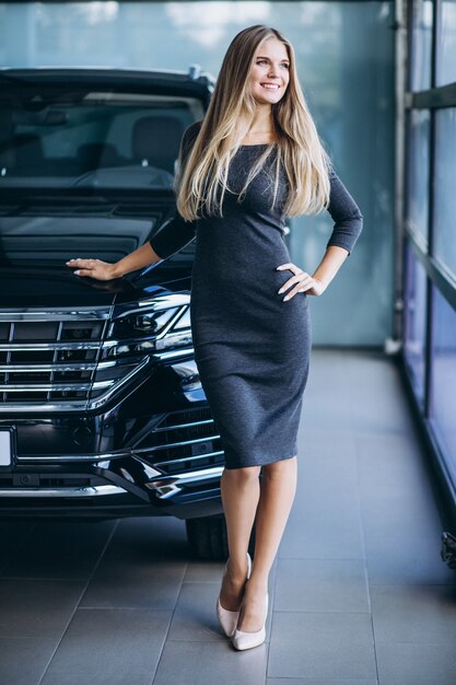 Giovane donna che sceglie un'automobile in una sala d'esposizione dell'automobile