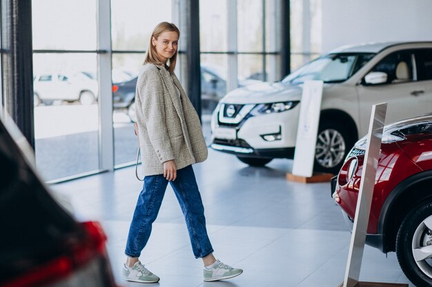 Giovane donna che sceglie un'automobile in una sala d'esposizione dell'automobile