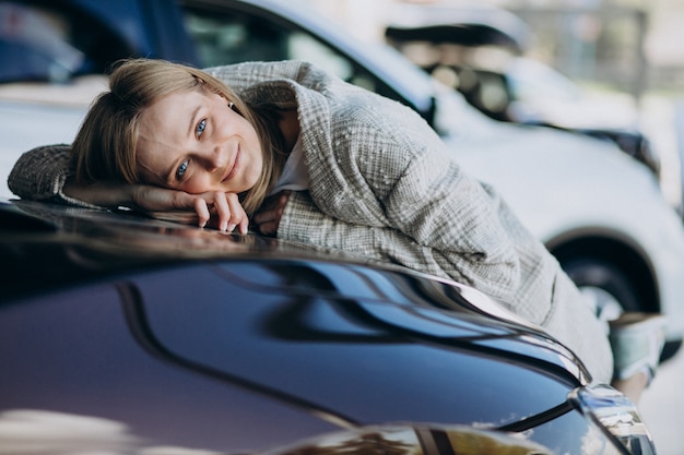 Giovane donna che sceglie un'automobile in una sala d'esposizione dell'automobile