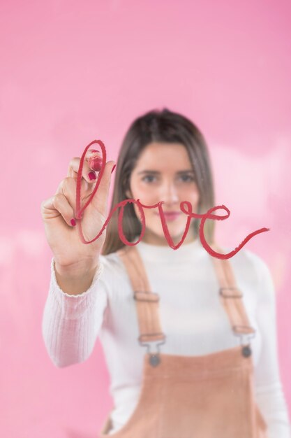 Giovane donna che scrive amore sul vetro con rossetto