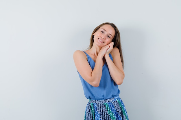 Giovane donna che si appoggia sulle mani come cuscino in singoletto, gonna e sembra carina