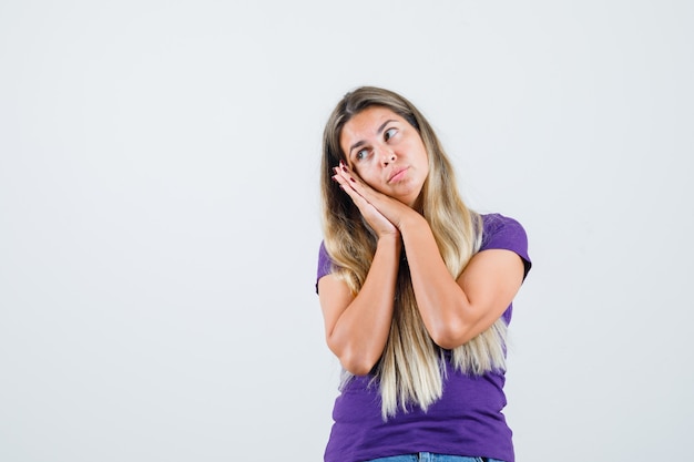 Giovane donna che si appoggia sulle palme come cuscino in maglietta viola e sembra carina. vista frontale.